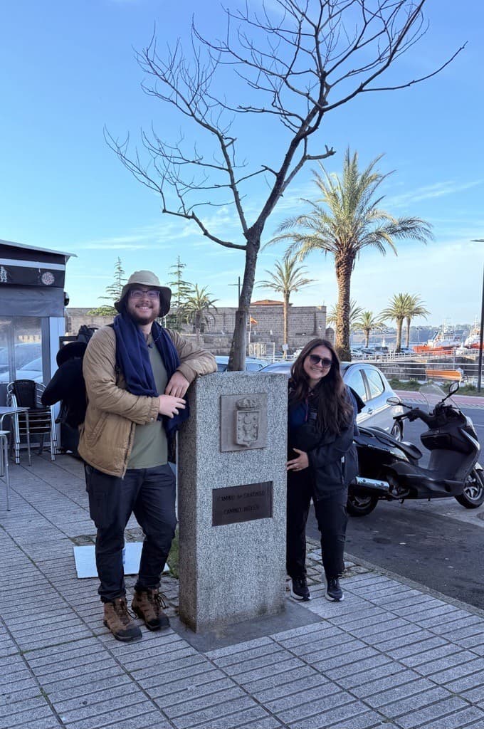 Two students stand on either side of a post located at the start of the Camino de Santiago pilgrimage.