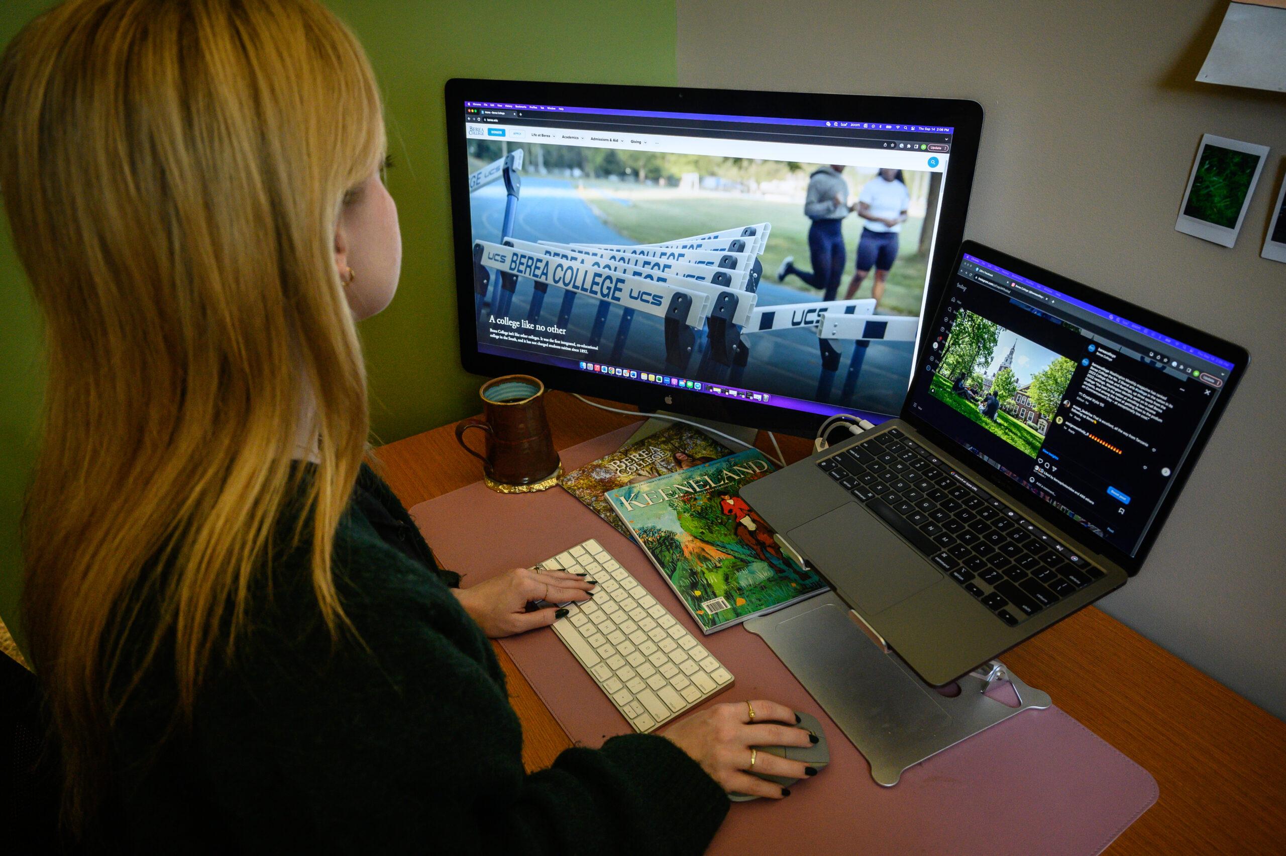 Berea College Marketing and Communications. A woman sits at a desk and looks at the Berea College website on computer.