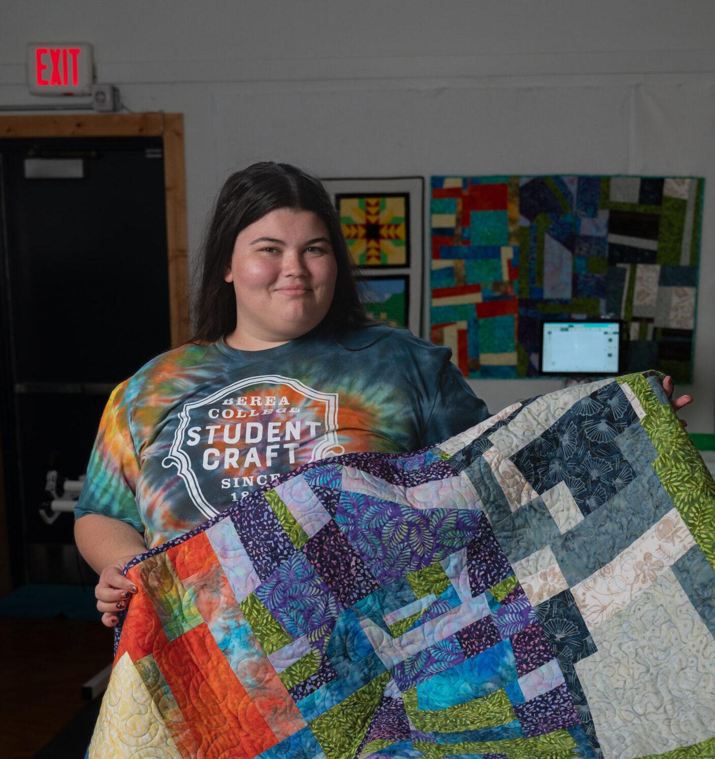 Berea student, Dani, holding up a quilt