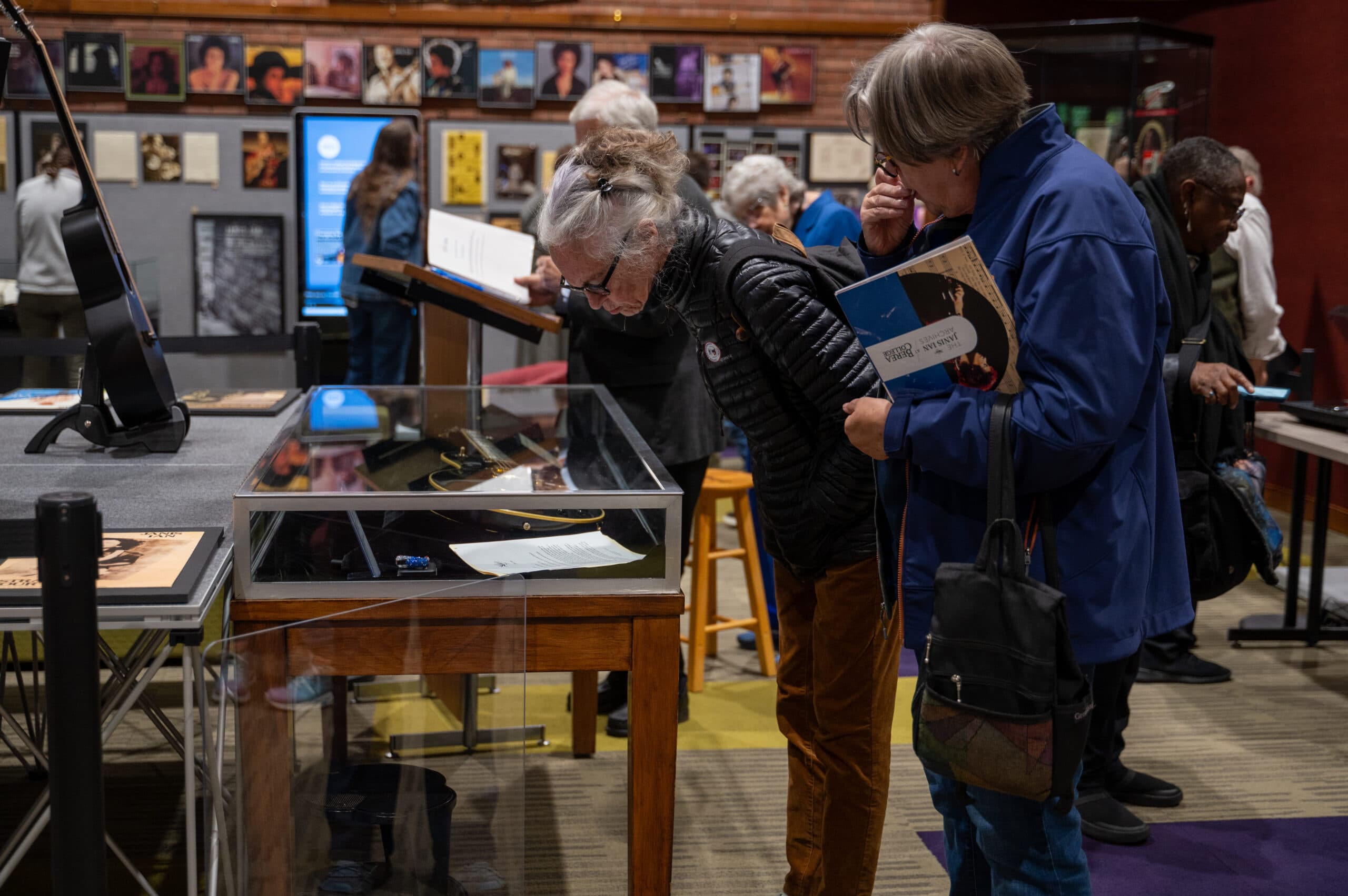 Visitors to Hutchins Library browse the Janis Ian Archives, observing glass displays and curated wall exhibits.